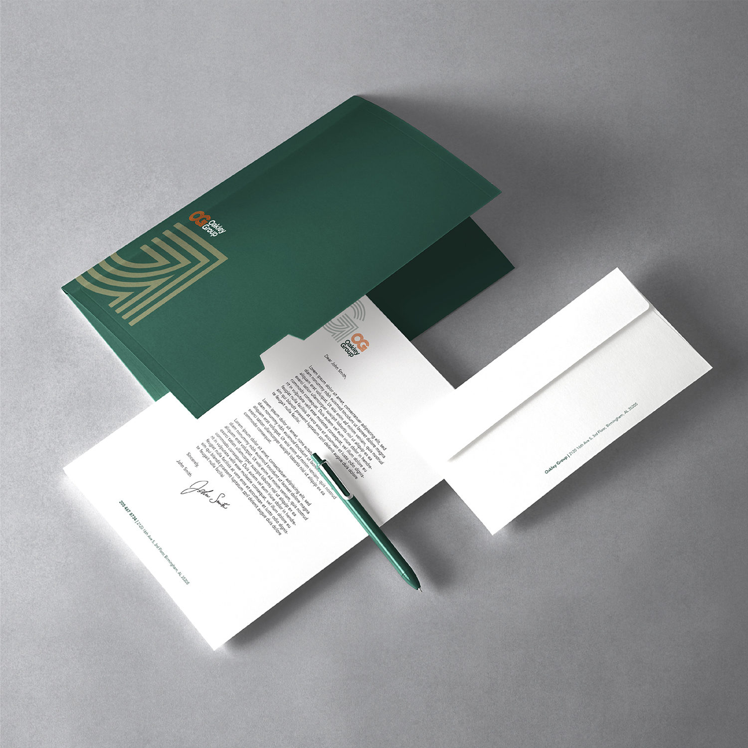 Mocked up stationery materials for Oakley Group. It depicts a green folder, cover letter example and an envelope with a pen sitting on top of the cover letter.