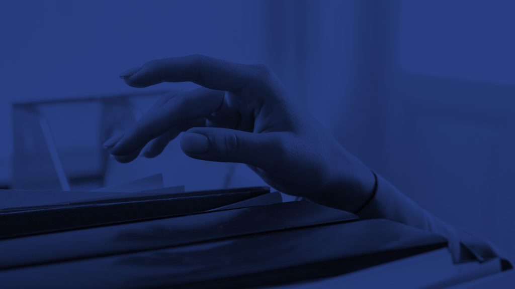 Close up photo of a hand reaching for a file. The entire photo has a dark blue tint overlay.